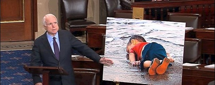 سناتور مک کین در کنار عکس کودک غرق شده سوری که چشم جهان را به روی جنایات بشار اسد در سوریه گشود