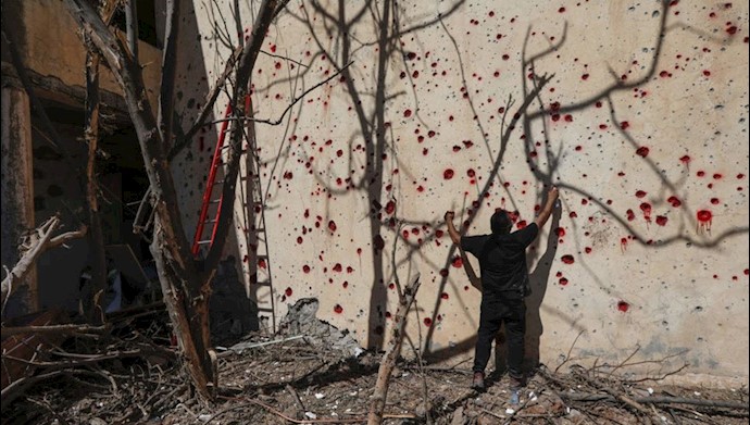فردی محل اصابت ترکشها بر روی دیوار را با رنگ قرمز علامت گذاری می‌کند