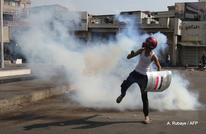 رزمنده شورشی در حال مقابله با شلیک گاز اشک‌آور