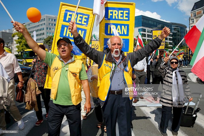 ایرانیان پرچمهای ملی ایران و پوسترهای را در دست دارند و در عین‌حال در یک راهپیمایی سازمان‌یافته برای یک ایران آزاد شرکت دارند 
