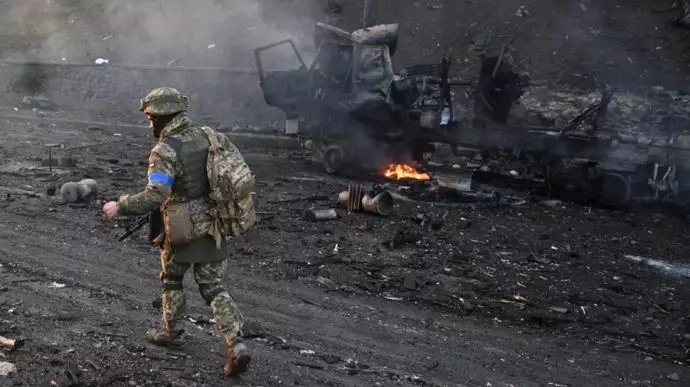 سرباز اوکراینی در حال عبور از خودروهای سوخته 