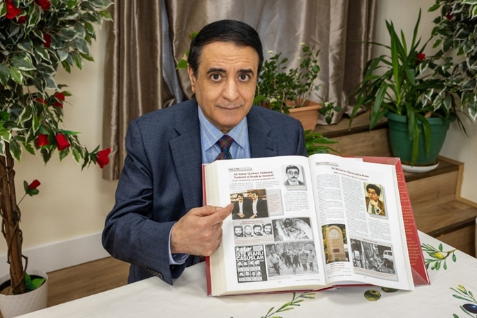 حسین عابدینی در دفتری در شمال لندن با کتابی که بیش از ۲۰هزار نفر را که توسط دولت ایران کشته شده‌اند