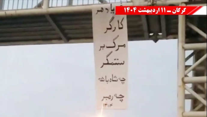 آویزان کردن بنر به‌مناسبت روز جهانی کارگر از پلی در گرگان